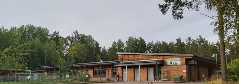 Modern skolbyggnad i trä omgivna av skog.
