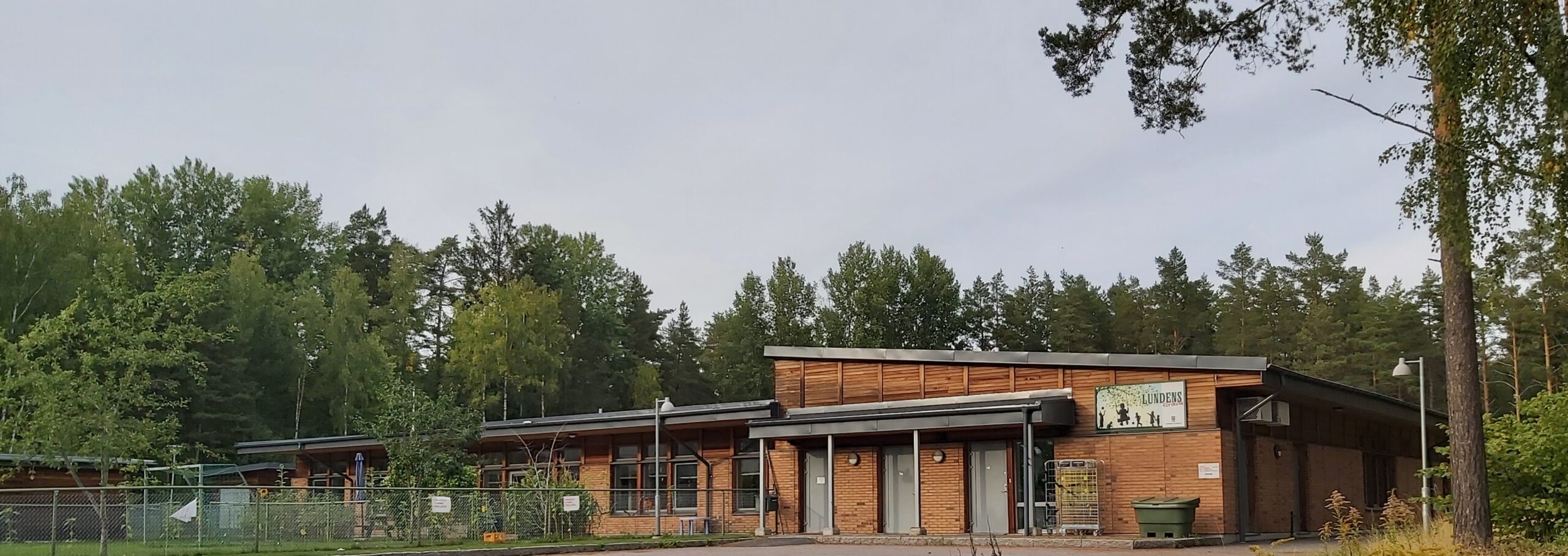 Lundens förskola Modern skolbyggnad i trä omgivna av skog.